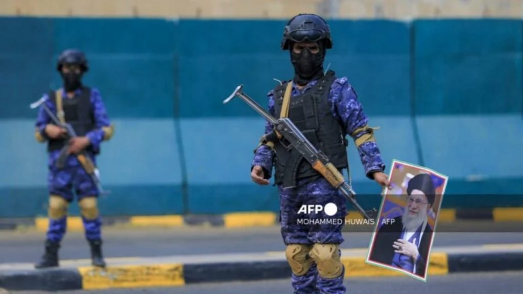 A masked fighter stands with a picture of Iran's supreme leader Ali Khamenei during a memorial rally held by supporters of Yemen's Huthis, a day after Khamenei was assassinated during US and Israeli strikes on Tehran, in the Huthi-held capital Sanaa on March 1, 2026