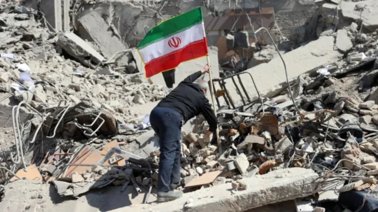 Iranian man placing a flag on rubble amid city destruction, Tehran