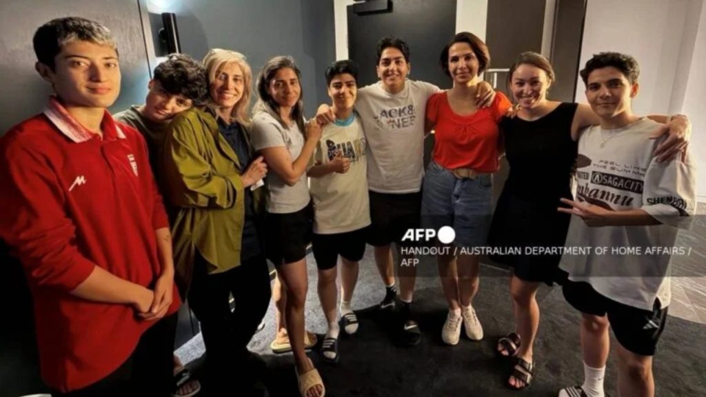 An undated photo released by Australia's Department of Home Affairs on March 11, 2026 shows two more members of the Iranian women's football team to claim asylum in Australia, player Mohaddeseh Zolfi (L) and support member Zahra Soltan Meshkeh Kar (3rd L), posing with their five other teammates who had earlier claimed asylum Fatemeh Pasandideh (2nd L), Atefeh Ramezanizadeh (4th L), Mona Hamoudi (C), Zahra Ghanbari (4th R), and Zahra Sarbali (R), along with two other local officials (2nd and 3rd R) in Sydney.