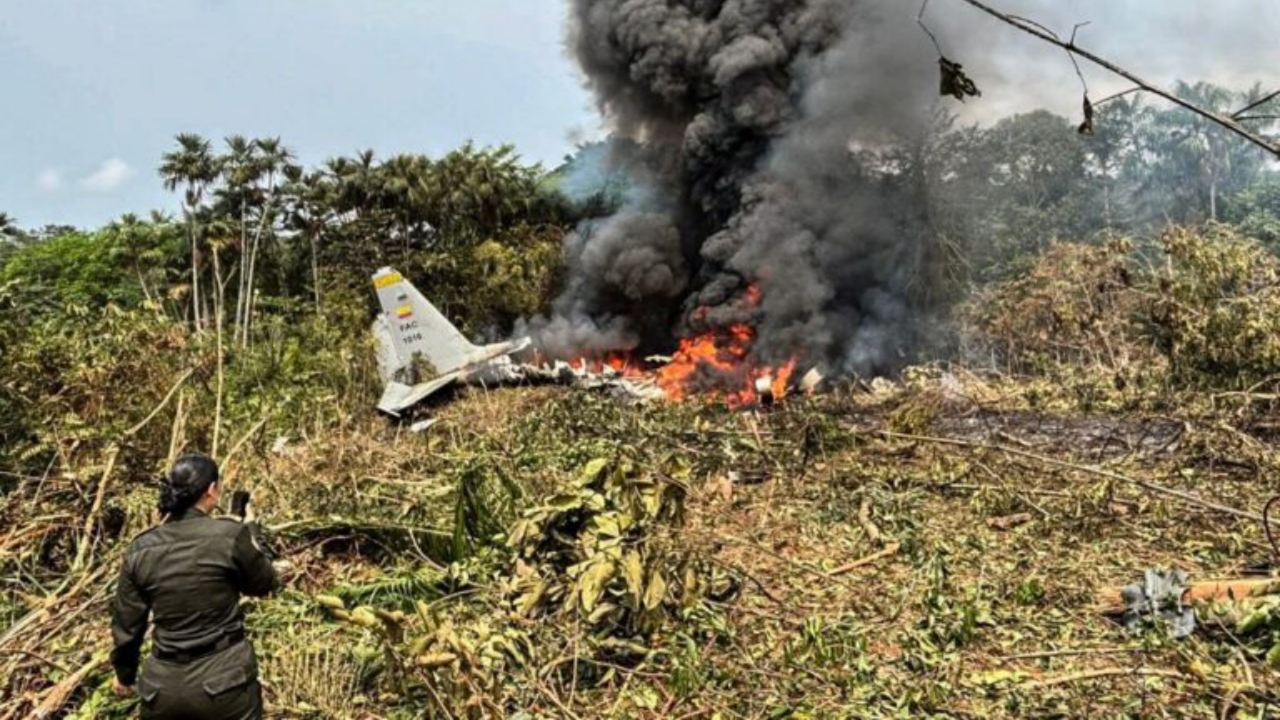 Flames and thick black smoke rise from an Air Force Hercules that crashed during takeoff, as a member of the Colombian Police stands nearby, in Puerto Leguizamo, Colombia, near the southern border with Ecuador, on March 23, 2026 - National News
