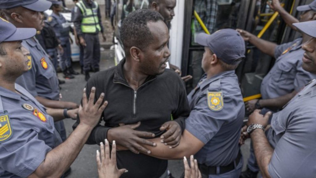Members of the South African Police Service (SAPS) escort a foreign national resisting to get into a bus from the Diakonia Centre to the Home Affairs offices in Durban on May 21, 2026 - National News